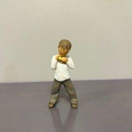 Small figurine of a child standing with hands near the chest