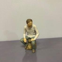 Small seated figurine of a person on a stool