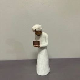 Small figurine in white robes holding a book
