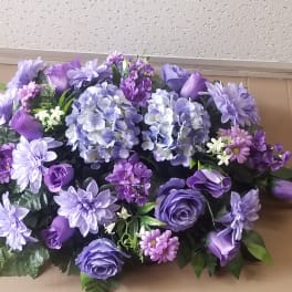 Purple floral arrangement with hydrangeas, roses, and daisies