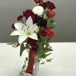 Red and white floral arrangement in a glittery high-heel vase with heart picks