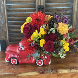 Colorful flower arrangement in a red ceramic truck container
