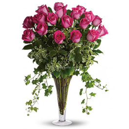 Pink roses in a tall clear vase with trailing ivy