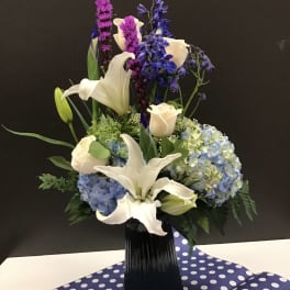 White lilies and blue hydrangeas in a black vase