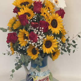Bouquet of sunflowers and red roses in a painted ceramic pitcher
