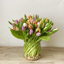 Bouquet of pink, white, and yellow tulips in a clear glass vase