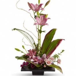 Tall pink lilies with orchids and roses in a low black rectangular container