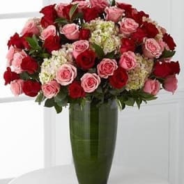 Large bouquet of red and pink roses in a tall green vase