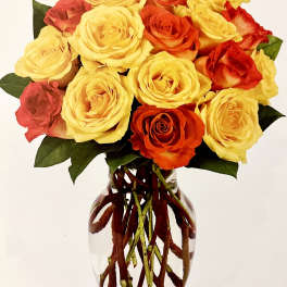 Bouquet of yellow, orange, and red roses in a clear glass vase