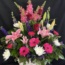 Mixed bouquet in a white basket with pink lilies, roses, and gerbera daisies