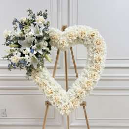 Heart-shaped floral wreath on an easel with white roses and lilies