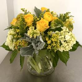 Yellow roses and white hydrangeas arranged in a clear glass vase.