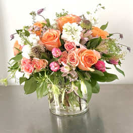 Mixed bouquet of orange and pink roses in a clear glass vase