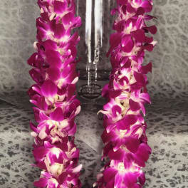 Purple orchid lei draped around a clear glass vase