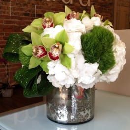 White hydrangeas and green orchids in a glass vase