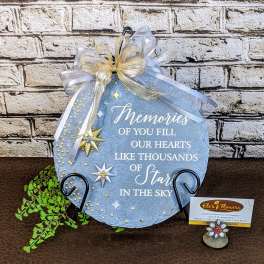 Blue memorial plaque with ribbon and star decorations on a stand