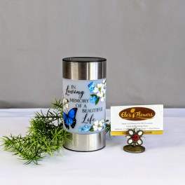 Memorial candle with floral butterfly design and a small greenery sprig