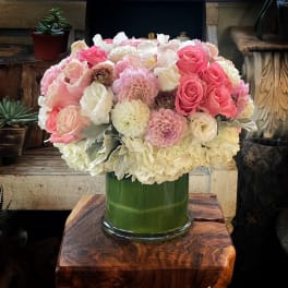 Pink and white flower arrangement in a green glass vase