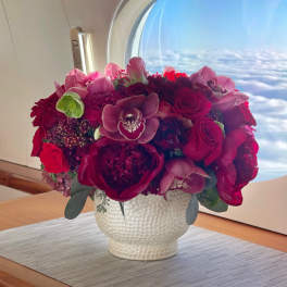 Bouquet of red and pink flowers in a white textured vase
