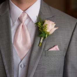 Pink boutonniere on a gray suit jacket with a matching pink tie