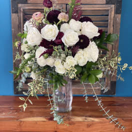 White and burgundy rose bouquet in a clear glass vase