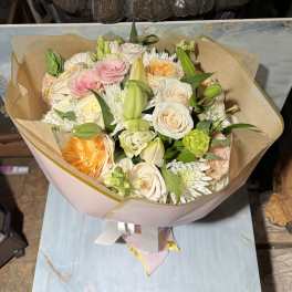 Bouquet of pink, white, and peach flowers wrapped in tan paper