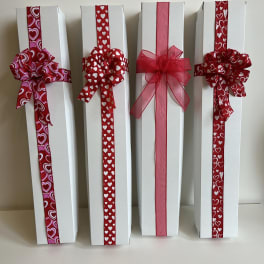 Four white gift boxes decorated with red heart ribbons and bows