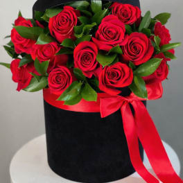 Red roses arranged in a black hat box with a red ribbon