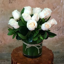 White roses in a green cylindrical vase tied with twine