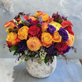 Mixed bouquet of roses, calla lilies, and dahlias in a stone vase