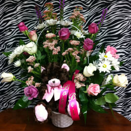 Bouquet of pink and white flowers with a teddy bear in a white basket