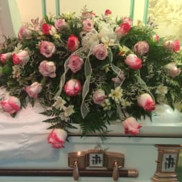 Pink and white rose casket spray with ribbon and greenery