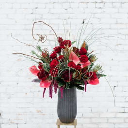 Tall red floral arrangement in a dark vase on a stand