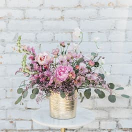 Pink and white flowers in a gold vase on a round table