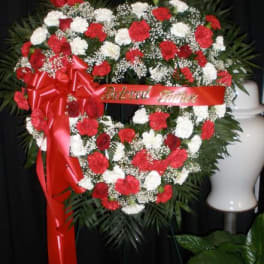 Heart-shaped red and white floral wreath with a red ribbon
