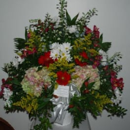 Large standing floral spray with mixed red, white, pink, and yellow flowers