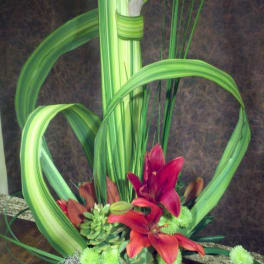 Tropical floral arrangement with red lilies in a blue bowl