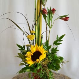 Tall floral arrangement with a sunflower and red alstroemeria in a red vase