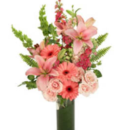 Pink lilies and gerbera daisies in a tall glass vase