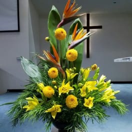 Tall tropical floral arrangement with yellow lilies and bird of paradise in a black vase
