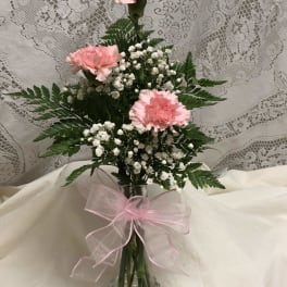 Pink carnations and white baby's breath in a glass vase with a pink bow