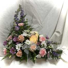 Pastel floral arrangement with roses, carnations, and daisies around a candle