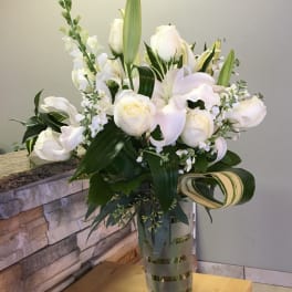 White roses and lilies arranged in a clear glass vase.