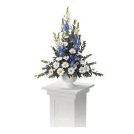 Blue and white floral arrangement in a white urn on a pedestal