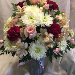 Mixed bouquet in a ribbed vase with pink roses, white mums, and burgundy carnations