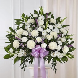 White floral standing spray with a lavender ribbon on a pedestal