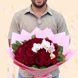 Man holding a bouquet of red roses with white orchids