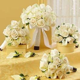 White rose and calla lily bouquets with ribbon on a gold table