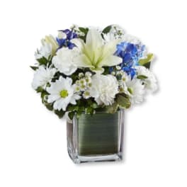 White and blue flowers arranged in a square glass vase