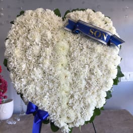 Heart-shaped white floral wreath with a blue ribbon reading SON